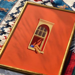 May include: Framed art print featuring an orange background with a gold frame. The artwork depicts a window with a person's legs and feet hanging out. The window is beige and the legs are tan with blue shorts. The artwork is on a colorful rug.