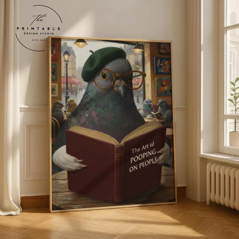 May include: A framed print featuring a pigeon wearing glasses and a beret, reading a book titled "The Art of Pooping on People." The image has a humorous, artistic style, with a cafe scene in the background.
