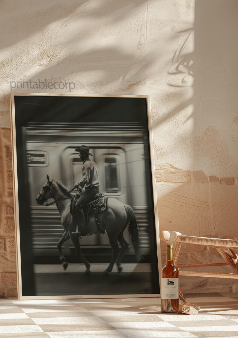May include: Black and white framed print featuring a cowboy riding a horse past a speeding train. The image has a vintage aesthetic. A bottle of wine sits in front of the print. The text "printablecorp" is visible in the upper left corner.
