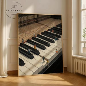 May include: A framed print featuring a piano keyboard with miniature figures walking on the keys. The black and white keys are in sharp focus, with the piano's internal mechanisms visible in the background. The print has a wooden frame and the text "The Printable Design Studio" in the upper left corner.
