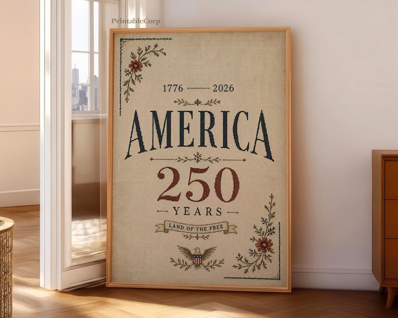 Pu&ograve; includere: Una stampa incorniciata con la parola "AMERICA" in un font vintage, che celebra 250 anni. Il design include elementi floreali, gli anni 1776-2026 e la frase "LAND OF THE FREE" con un emblema dell'aquila. La stampa ha uno sfondo beige.