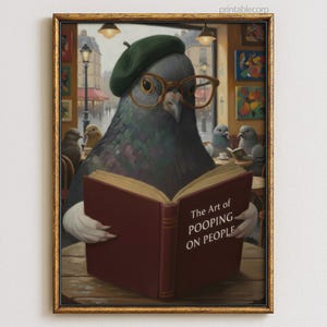 May include: A framed print featuring a pigeon wearing glasses and a beret, reading a book titled "The Art of Pooping on People." The artwork has a vintage style, with a gold frame and a cafe setting.