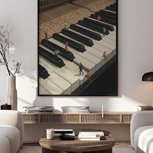 May include: Framed art print featuring a surreal image of a piano keyboard with miniature figures walking on the keys. The artwork has a black frame and is displayed in a modern living room setting. The text "printablecorp" is visible in the top left corner.