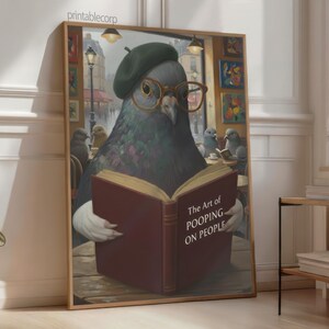 May include: A framed print featuring a pigeon wearing a beret and glasses, reading a book titled "The Art of Pooping on People." The artwork has a humorous theme, with other pigeons in the background. The print is displayed in a room with natural light.