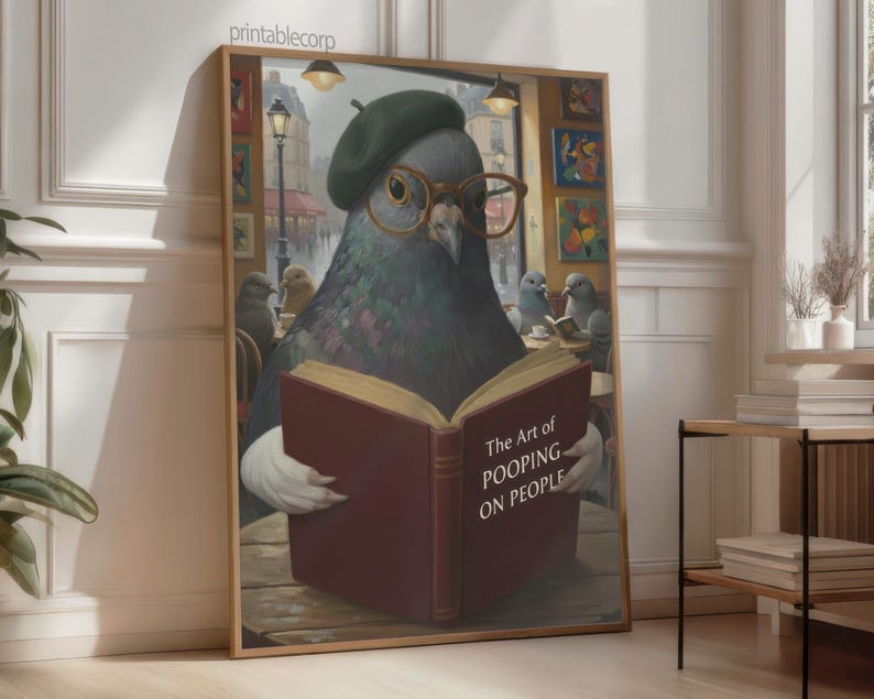 May include: A framed print featuring a pigeon wearing a beret and glasses, reading a book titled "The Art of Pooping on People." The artwork has a humorous theme, with other pigeons in the background. The print is displayed in a room with natural light.