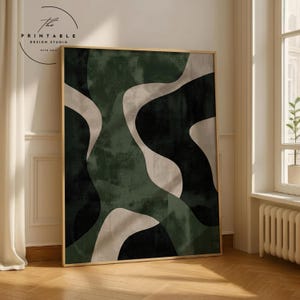 Puede incluir: Gran impresión artística abstracta enmarcada con formas fluidas en tonos verdes, negros y beige. La obra de arte se exhibe en una habitación con ventana y suelo de madera. El texto "The Printable Design Studio" está en la esquina superior izquierda.