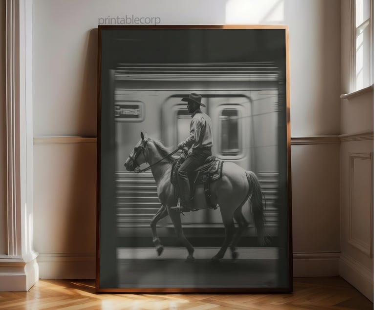 May include: Black and white framed print featuring a cowboy riding a horse in front of a blurred train. The print has a sepia tone and the text "printablecorp" is in the top left corner.