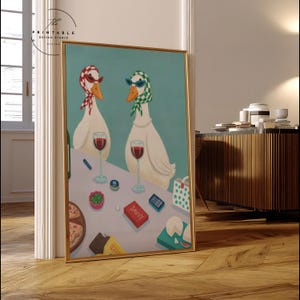May include: A framed art print featuring two white geese wearing sunglasses and scarves, enjoying wine. The table includes pizza, cheese, and a box labeled "SAVVY." The background is a light teal color.