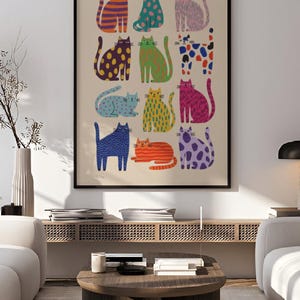 Puede incluir: Un p&oacute;ster enmarcado con ilustraciones de gatos coloridos. Cada gato est&aacute; representado con un patr&oacute;n y color &uacute;nicos, incluyendo rayas naranjas, lunares azules y manchas moradas. El p&oacute;ster tiene el texto "printablecorp" en la esquina superior izquierda.