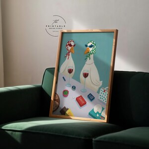 May include: A framed art print featuring two white geese wearing sunglasses and headscarves, standing at a table with wine glasses and snacks. The word "SAVVY" is visible on a red box. The print is in a wooden frame.