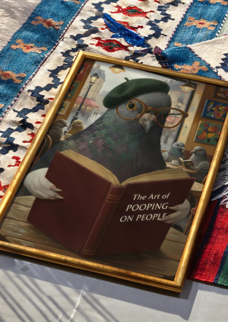 May include: Framed artwork featuring a pigeon wearing a green beret and glasses, reading a book titled "The Art of Pooping on People." The artwork has a gold frame and depicts a Parisian cafe scene.