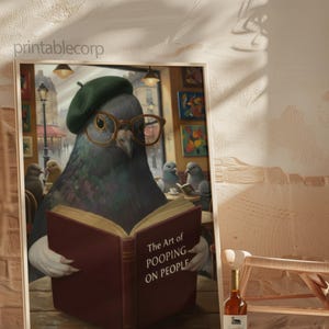 May include: A framed art print featuring a pigeon wearing glasses and a beret, reading a book titled "The Art of Pooping on People." The artwork has a humorous theme, with other pigeons in the background. A bottle of wine is in the foreground.