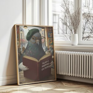 May include: A framed print featuring a pigeon wearing a green beret and glasses, reading a book titled "The Art of Pooping on People." The artwork has a humorous theme, with other pigeons in the background.
