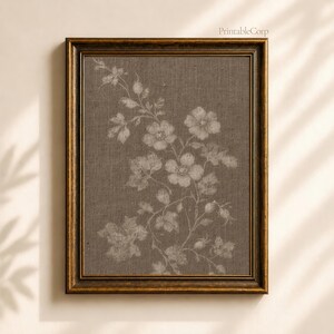 May include: A framed print featuring a floral botanical design. The artwork showcases a detailed illustration of flowers and leaves in a muted white hue against a textured brown background. The frame is a dark, ornate gold color. The text "PrintableCorp" is in the top right corner.