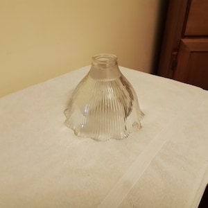 May include: A clear glass lampshade with a fluted design and a scalloped edge.