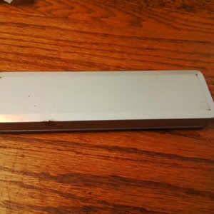 May include: A white rectangular tin box with a slightly worn surface.