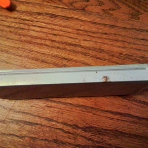 May include: A white rectangular case with a slightly textured surface. The case has a small amount of rust on the top.