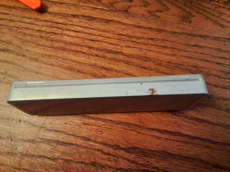 May include: A white rectangular case with a slightly textured surface. The case has a small amount of rust on the top.