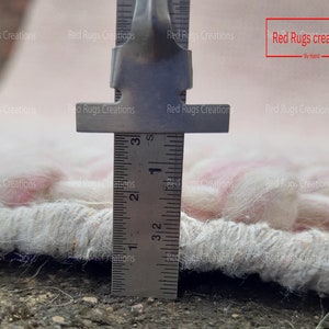 May include: Close-up of a white and pink rug with a ruler measuring the fringe. The ruler shows a measurement of 3 1/2 inches.