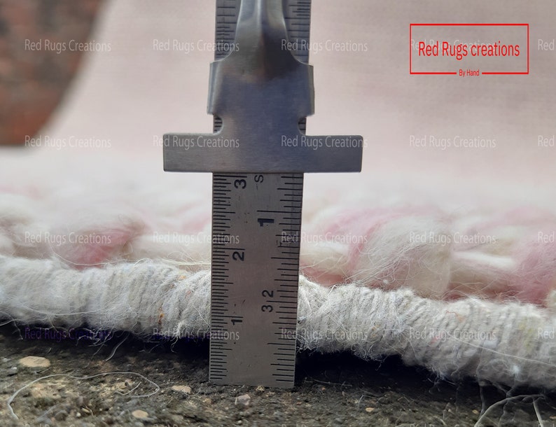 May include: Close-up of a white and pink rug with a ruler measuring the fringe. The ruler shows a measurement of 3 1/2 inches.