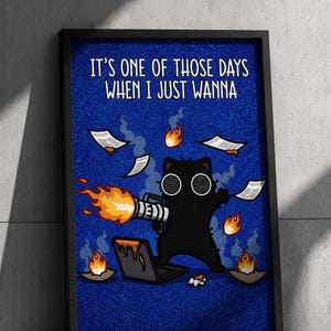 May include: A framed poster featuring a black cat with white circular eyes holding a flamethrower, standing over a burning laptop. The text reads, IT'S ONE OF THOSE DAYS WHEN I JUST WANNA. Burning papers float in the air against a blue background.