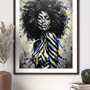 May include: Abstract portrait art print of a person with zebra-striped face and torso, and a large afro. The artwork features black, white, blue, and yellow paint splatters on a gray background, framed in a dark brown frame.