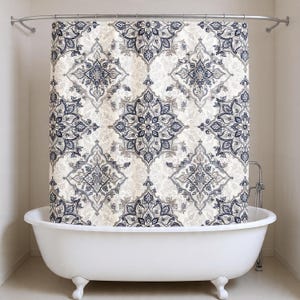 May include: A white clawfoot bathtub with a patterned shower curtain. The curtain features a repeating design in navy blue, gray, and beige. The shower curtain is hanging from a curved metal rod.