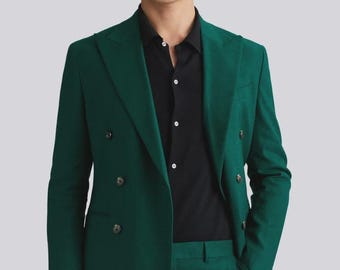 May include: A double-breasted suit jacket and matching trousers in a deep green colour. The jacket has four buttons and a single button on the sleeve. The model is wearing a black shirt underneath.