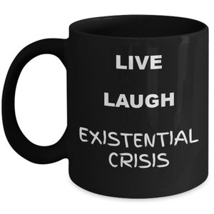 May include: Black coffee mug with white text that reads "Live Laugh Existential Crisis".