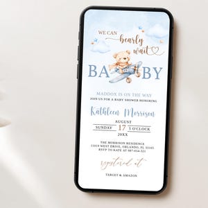 May include: A blue and white baby shower invitation with a cartoon teddy bear flying a plane. The text reads "We can barely wait" and "Baby". The invitation includes the date, time, and location of the shower, as well as the name of the honoree, Kathleen Morrison. The invitation also includes the text "registered at Target & Amazon".