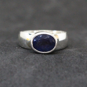 Könnte beinhalten: Ein silberner Ring mit einem dunkelblauen ovalen Edelstein.