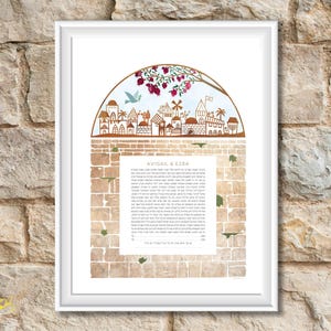 May include: A framed print featuring a watercolor illustration of a town scene with a brick wall design. The artwork includes a decorative arch with a tree and a dove. The text "AVIGAIL & EZRA" is visible.