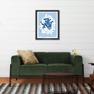 a living room with a green sofa, a brown leather armchair, and a black wire coffee table. Above the sofa, there is a framed picture with a blue and white design. The room also has a potted plant, a rug, and a white wall.