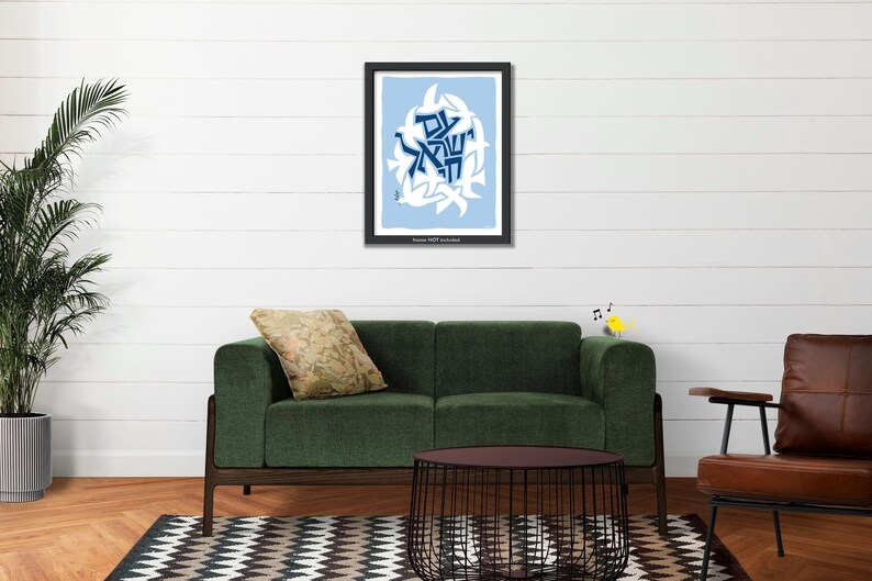 a living room with a green sofa, a brown leather armchair, and a black wire coffee table. Above the sofa, there is a framed picture with a blue and white design. The room also has a potted plant, a rug, and a white wall.