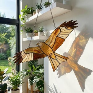 May include: Stained glass bird sculpture in flight, featuring shades of brown, tan, and cream. The bird is suspended by chains, with a detailed depiction of feathers and a realistic bird head. The sculpture casts a shadow on the wall.