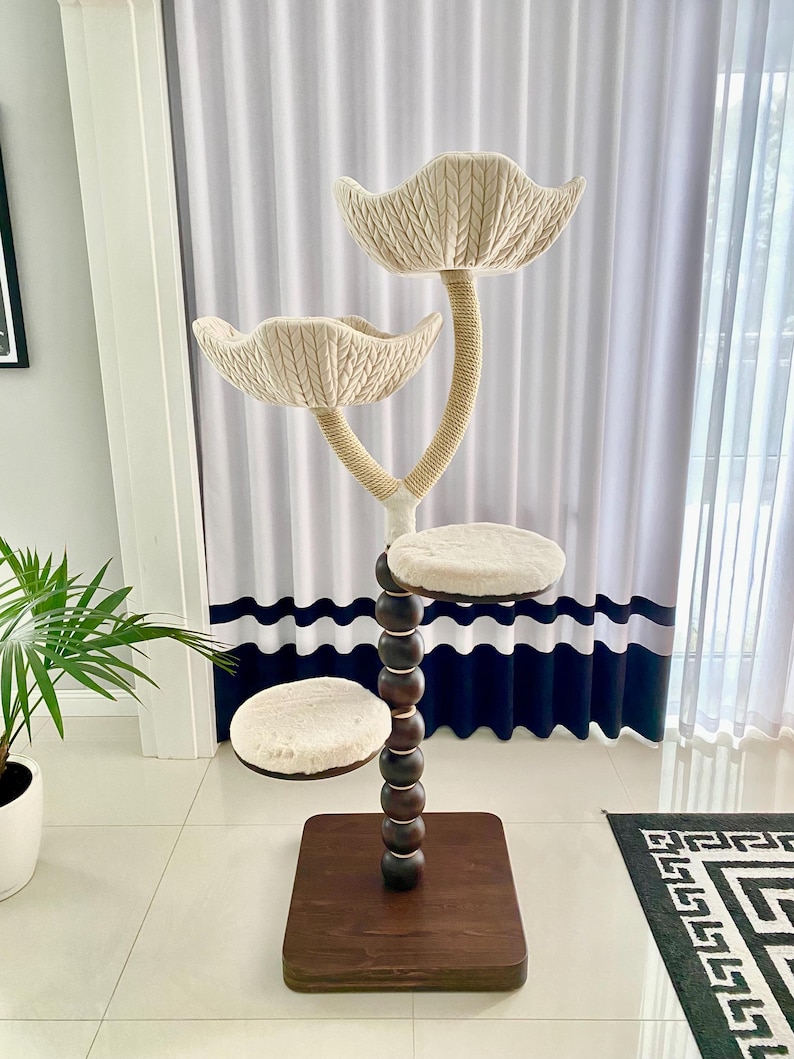 Pode incluir: Uma &aacute;rvore para gatos bege com tr&ecirc;s plataformas e um poste alto marrom com contas de madeira. As plataformas s&atilde;o cobertas com tecido macio bege e o poste &eacute; envolto em corda de sisal. A &aacute;rvore para gatos est&aacute; sobre uma base de madeira marrom.