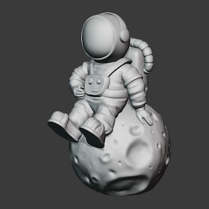 May include: A white astronaut figurine sitting on a gray moon with craters. The astronaut is wearing a helmet and a spacesuit.