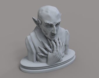 May include: A gray bust of a vampire with sharp features, long fingers, and pointed ears. The sculpture is set on a tiered, oval base. The vampire's expression is intense, with a furrowed brow and open mouth.