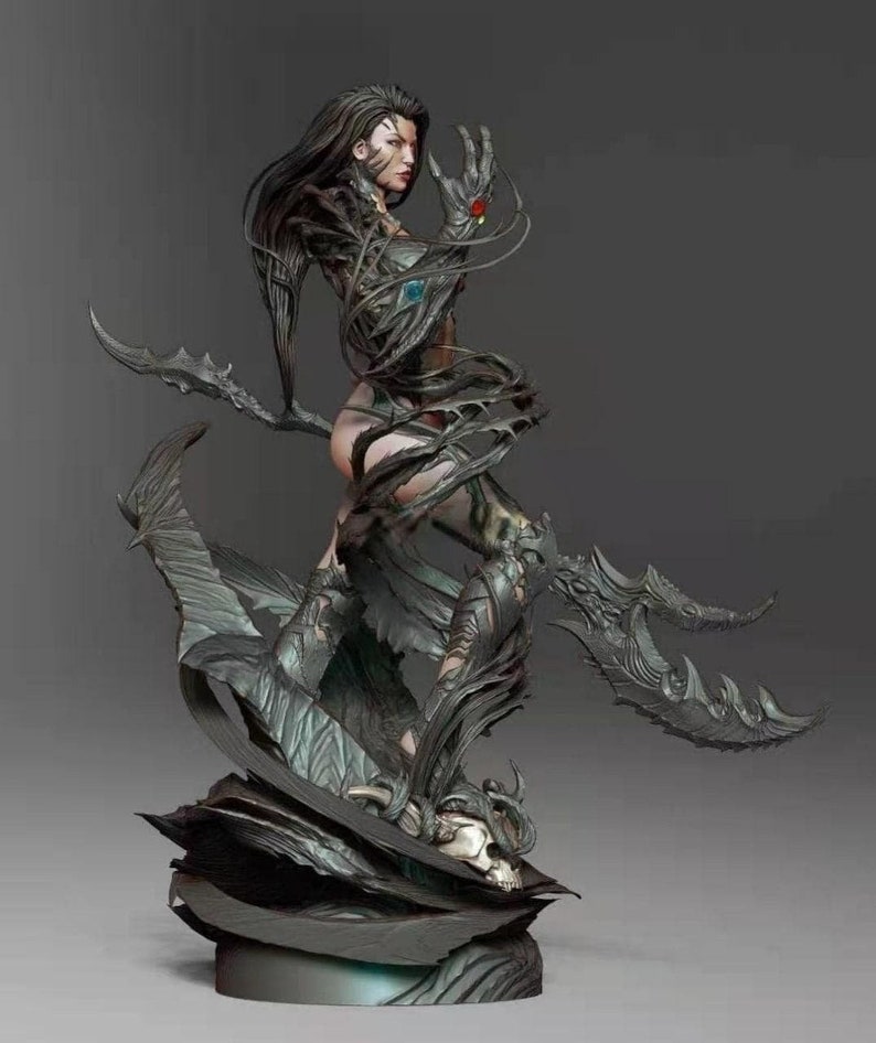 May include: A dark gray and black detailed figurine of a woman with long black hair and a flowing cape. The woman is standing on a base with a skull. The figurine is made of resin and is approximately 12 inches tall.