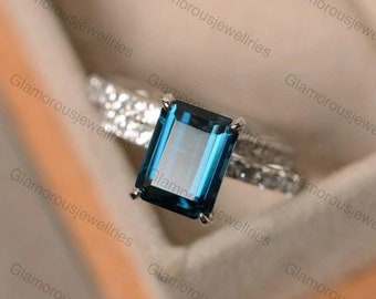 Anello di fidanzamento con topazio blu di Londra taglio smeraldo: oro bianco 14 carati con pavé di diamanti.
