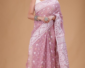 May include: A light purple saree with white geometric patterns and a decorative border. The saree is draped over a white sleeveless top. The saree has a diamond pattern and is worn with silver jewelry.