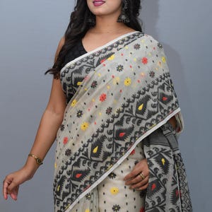 May include: A white saree with black, red, and yellow floral patterns. The saree has a geometric design with black and white accents.