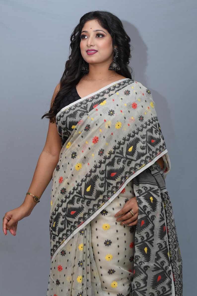 May include: A white saree with black, red, and yellow floral patterns. The saree has a geometric design with black and white accents.