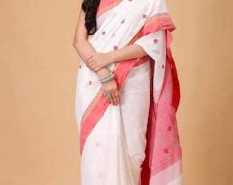 May include: White saree with a red border and small red square patterns. The saree has a simple design with a contrasting red border and a matching pallu. The fabric appears to be lightweight and suitable for warm weather.