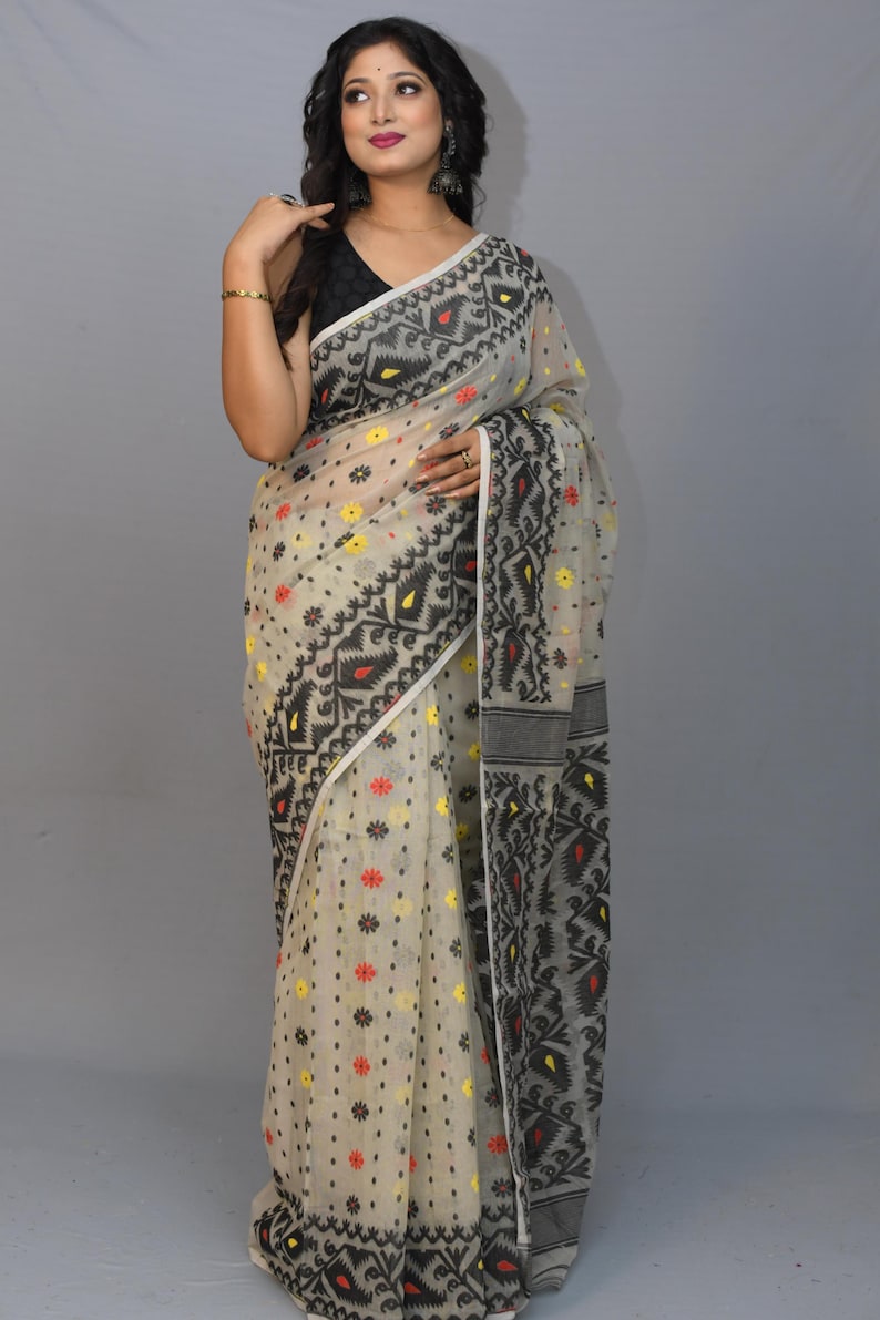 May include: A white saree with black and red floral patterns. The saree has a black border with intricate designs.