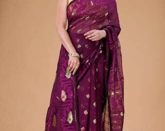 May include: A woman wearing a deep purple saree with gold accents. The saree features intricate patterns and a sheer, flowing fabric. The woman is also wearing gold jewelry, including a necklace and bracelet.