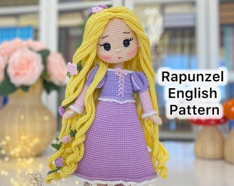 May include: A handmade crochet doll of Rapunzel with long yellow hair, wearing a purple dress. The doll has a sweet expression and is adorned with small floral accents. The text "Rapunzel English Pattern" is visible.