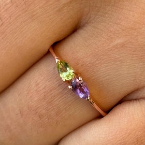 Peut inclure: Une délicate bague en or avec une pierre précieuse verte en forme de poire et une pierre précieuse violette en forme de poire.