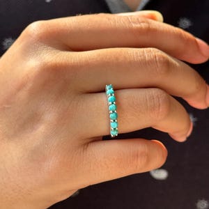 Pode incluir: Um anel de eternidade de turquesa. O anel é feito de prata e tem uma fila de pedras turquesa.
