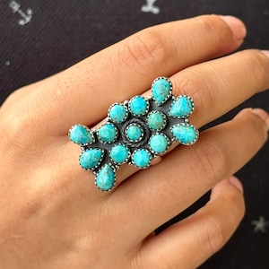 May include: A turquoise and silver ring with a cluster of turquoise stones set in a silver band.